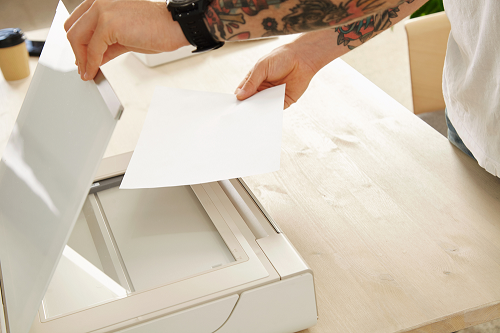 Female hands placing paper inside copier machine