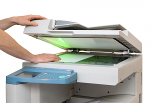 Hand placing sheet of paper under copier hood 