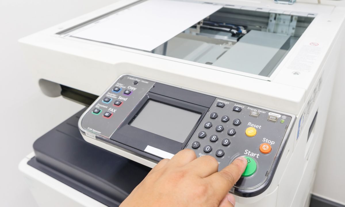 a person's hand on copier buttons