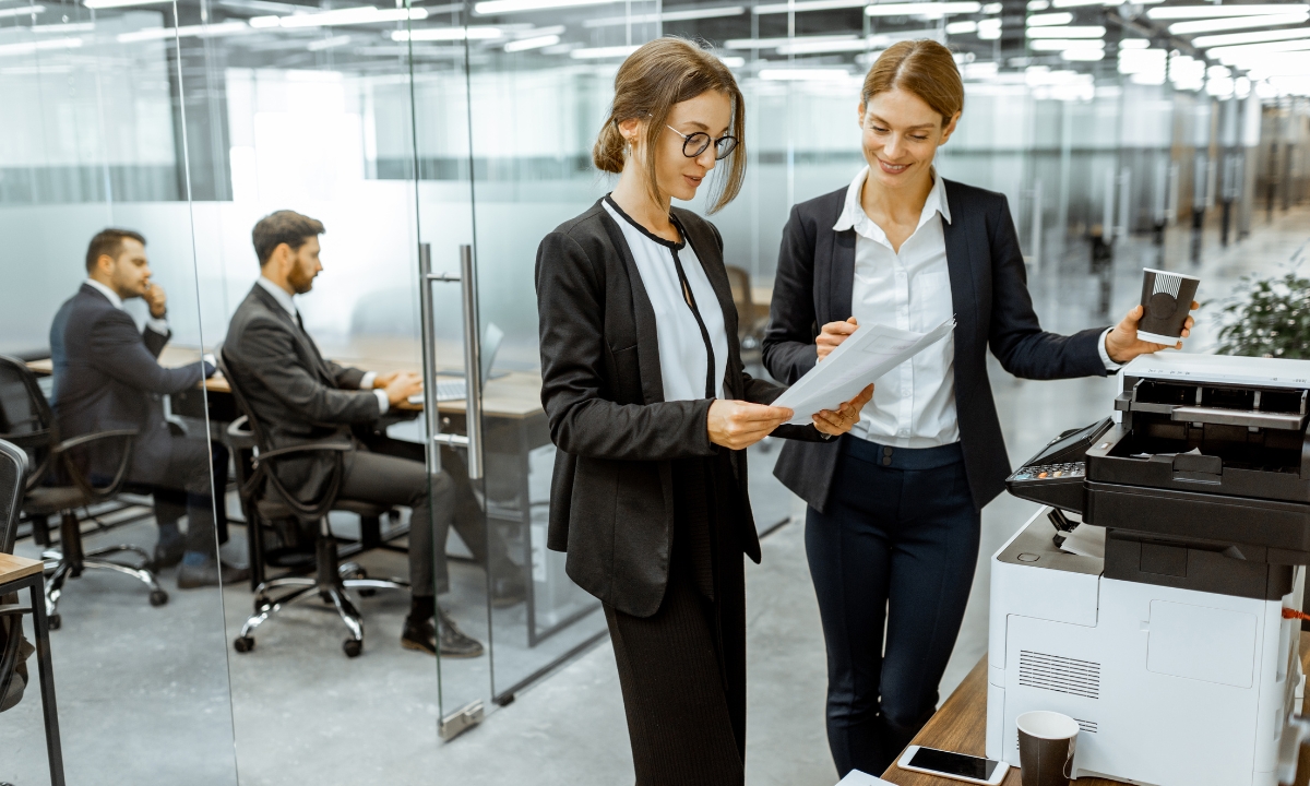 two people in an office building standing by a photocopier